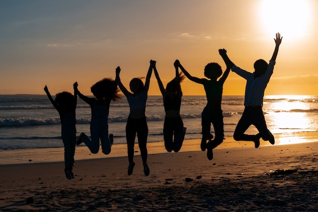 Photo gratuite silhouettes complètes de personnes sautant au coucher du soleil