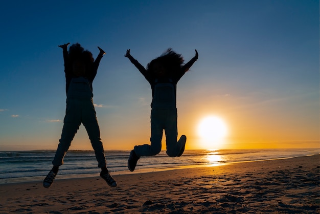 Photo gratuite silhouettes complètes de personnes sautant au coucher du soleil