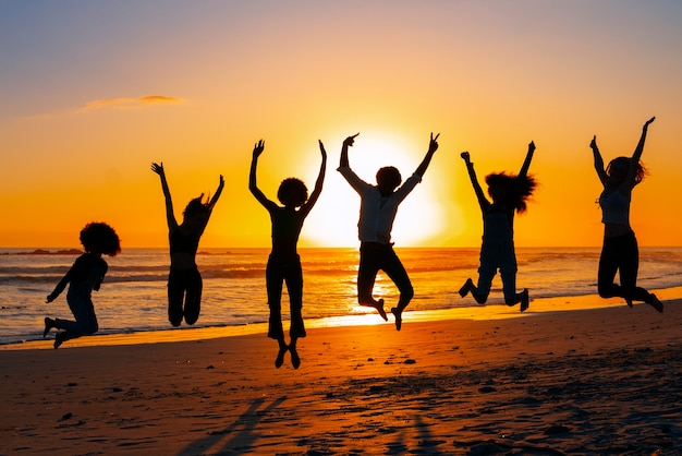 Photo gratuite silhouettes complètes de personnes sautant au coucher du soleil