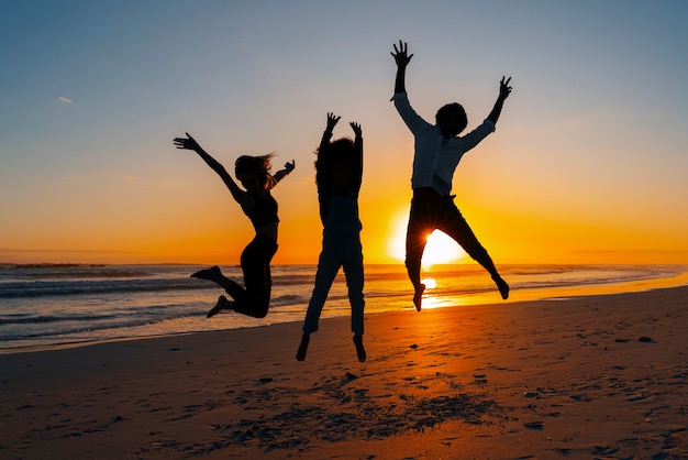 Photo gratuite silhouettes complètes de personnes sautant au coucher du soleil