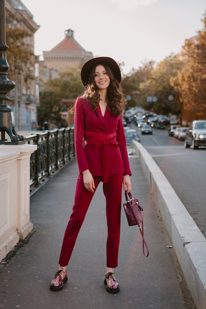 Photo gratuite superbe belle femme élégante en costume violet marchant dans la rue de la ville, tendance de la mode printemps été saison automne portant chapeau, tenant sac à main