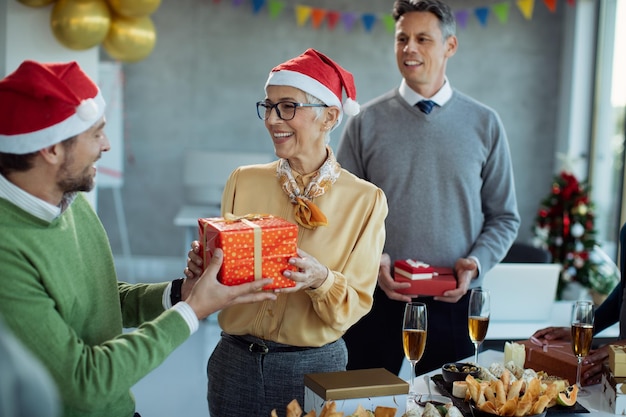 Heureuse femme d'affaires mature recevant un cadeau de Noël lors d'une fête de bureau