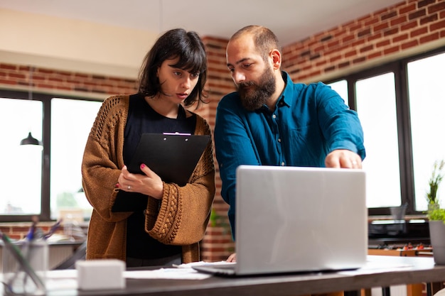 Photo homme d'affaires expliquant des idées de marketing à une femme gestionnaire montrant le débit de données sur un ordinateur portable discutant de la stratégie de l'entreprise. collègues travaillant à la présentation d'entreprise dans le bureau de démarrage