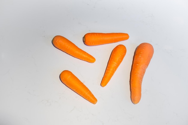 Foto carota fresca distesa su una tavola di marmo bianco sullo sfondo con luce dura e ombra