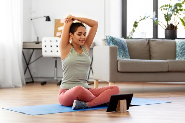 Foto donna felice con un tablet che fa sport a casa