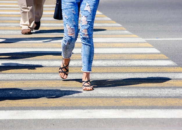 Foto sezione bassa di persone che attraversano la strada in città