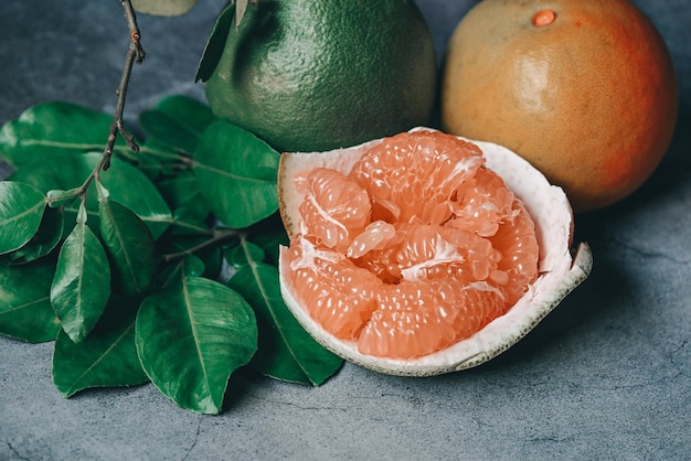 Foto frutta di pomelo su sfondo scuro pomelo fresco sbucciato sulla pelle di pomelo e foglie verdi dal pomelo pomelo pommel grapefruit in estate frutta tropicale in thailandia