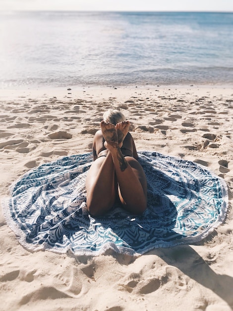 Foto vista posteriore di una donna sdraiata su una coperta sulla spiaggia