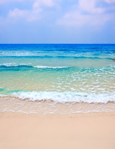 Foto onda del mare sulla spiaggia di sabbia contro il cielo nuvoloso