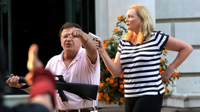 Armed homeowners Mark T. and Patricia N. McCloskey stand in front their house as they confront protesters marching to St. Louis Mayor Lyda Krewson's house on June 28, 2020.