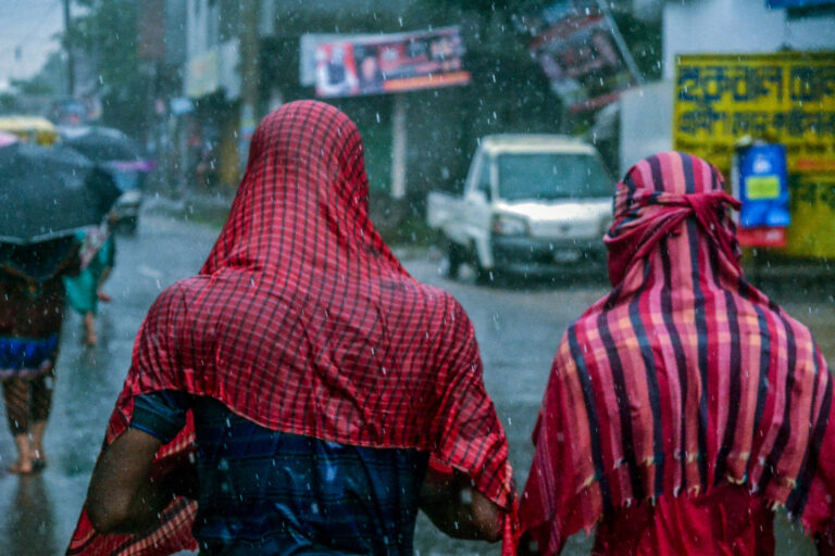 People walk in heavy rains in Dhaka.