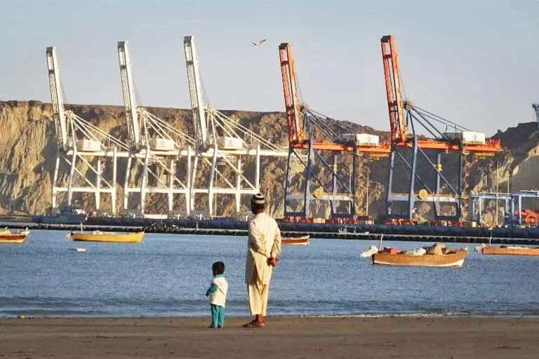 Residents from Gwadar look on the sipping development at the coast.