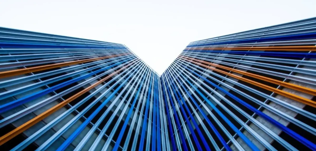 A colorful building with blue and orange stripes stands against a clear blue sky, highlighting its strategic edge.