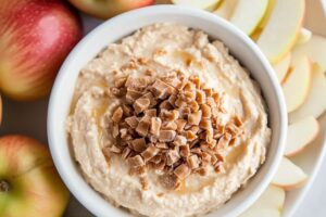 Toffee apple dip served in a white bowl surrounded by apple slices.