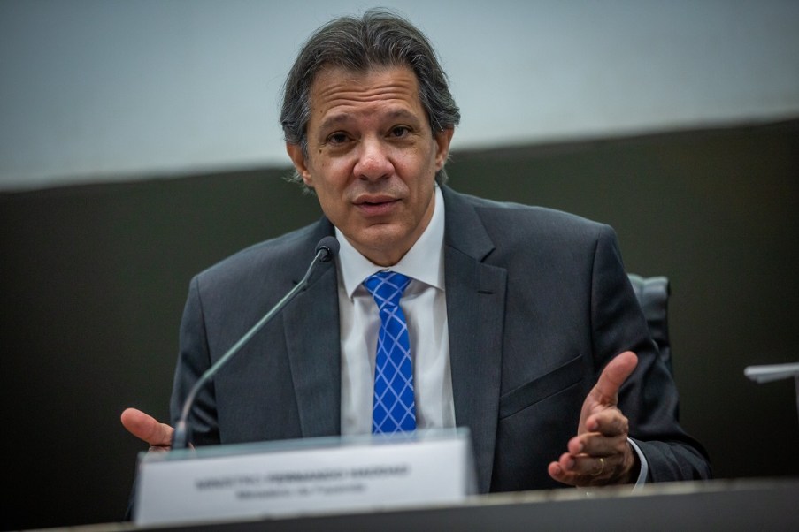 Foto do ministro da Fazenda, Fernando Haddad, que ilustra matéria sobre pacote de ajuste fiscal. Ele é homem, branco e usa terno cinza e gravata azul