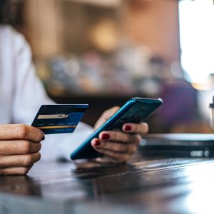 Pessoa mexendo com telefone celular e cartão de crédito