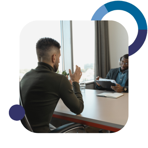 Two people sitting at a table talking to each other.