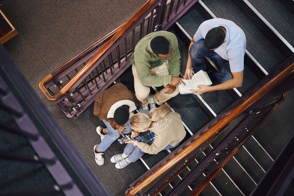 Above, student group and stairs for study together, thinking and research for exam, test or education. Students, diversity and teamwork for support, ideas and collaboration at university for mission