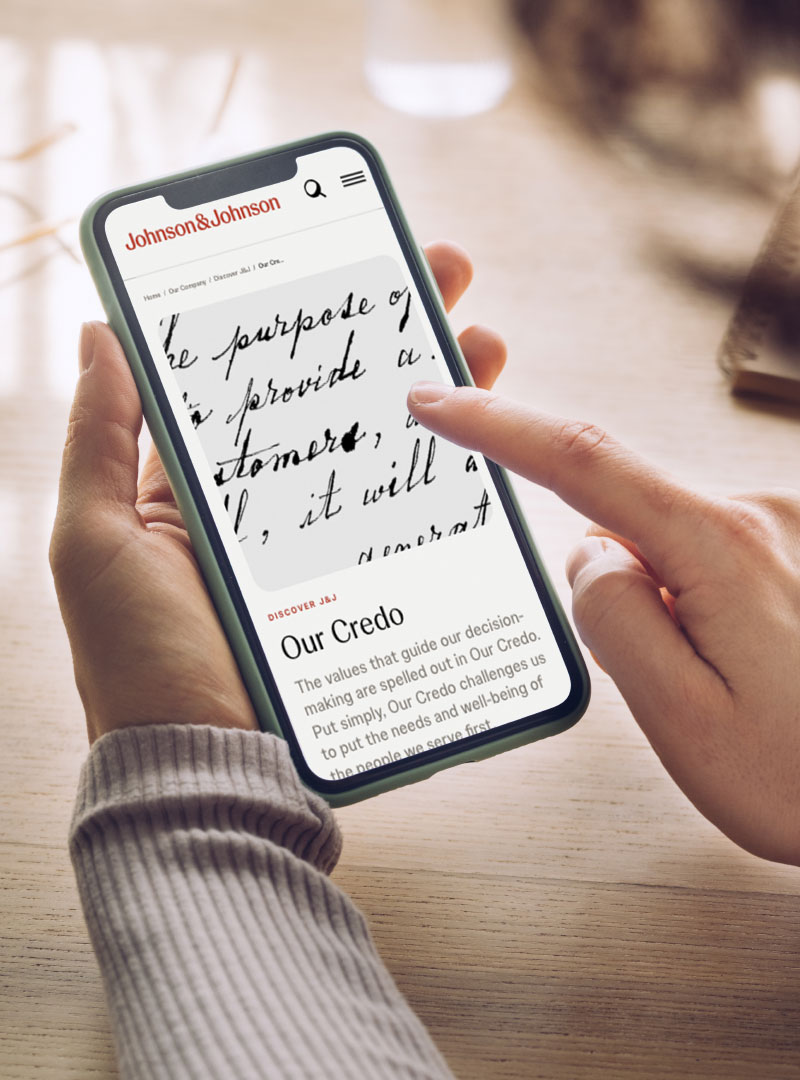 A person using their smartphone to view the Our Credo page on the Johnson & Johnson website 