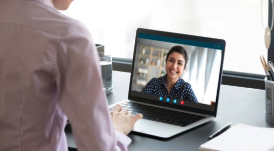 Woman smiling on a video call with a man in a tan shirt