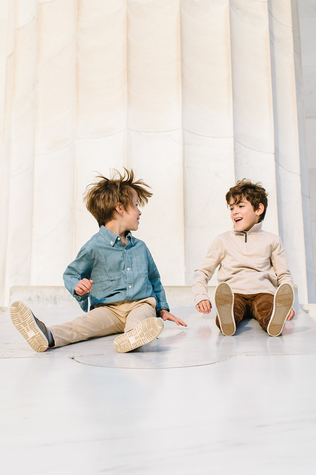 little boys playing and laughing while sitting in front of a column