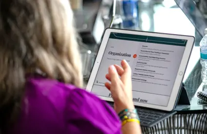 Close up of a tablet with a page up that says "organization" with a woman's hand in front of the screen