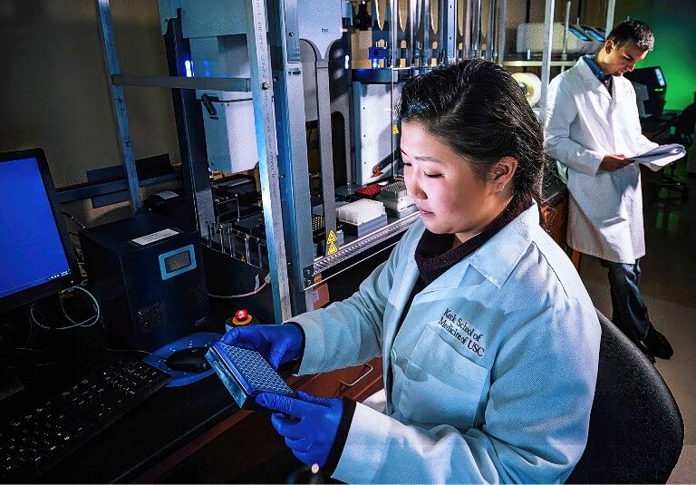 Female researcher in foreground, male in background, at the Keck School of Medicine of USC.