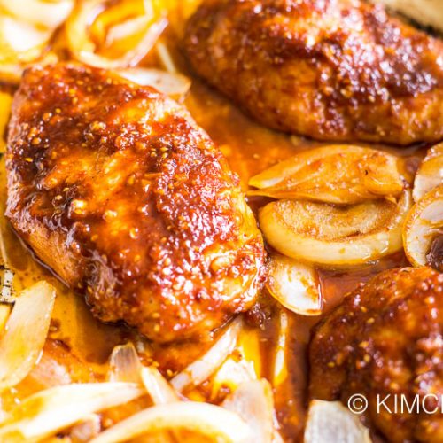 baked chicken on parchment paper with onions caramelized