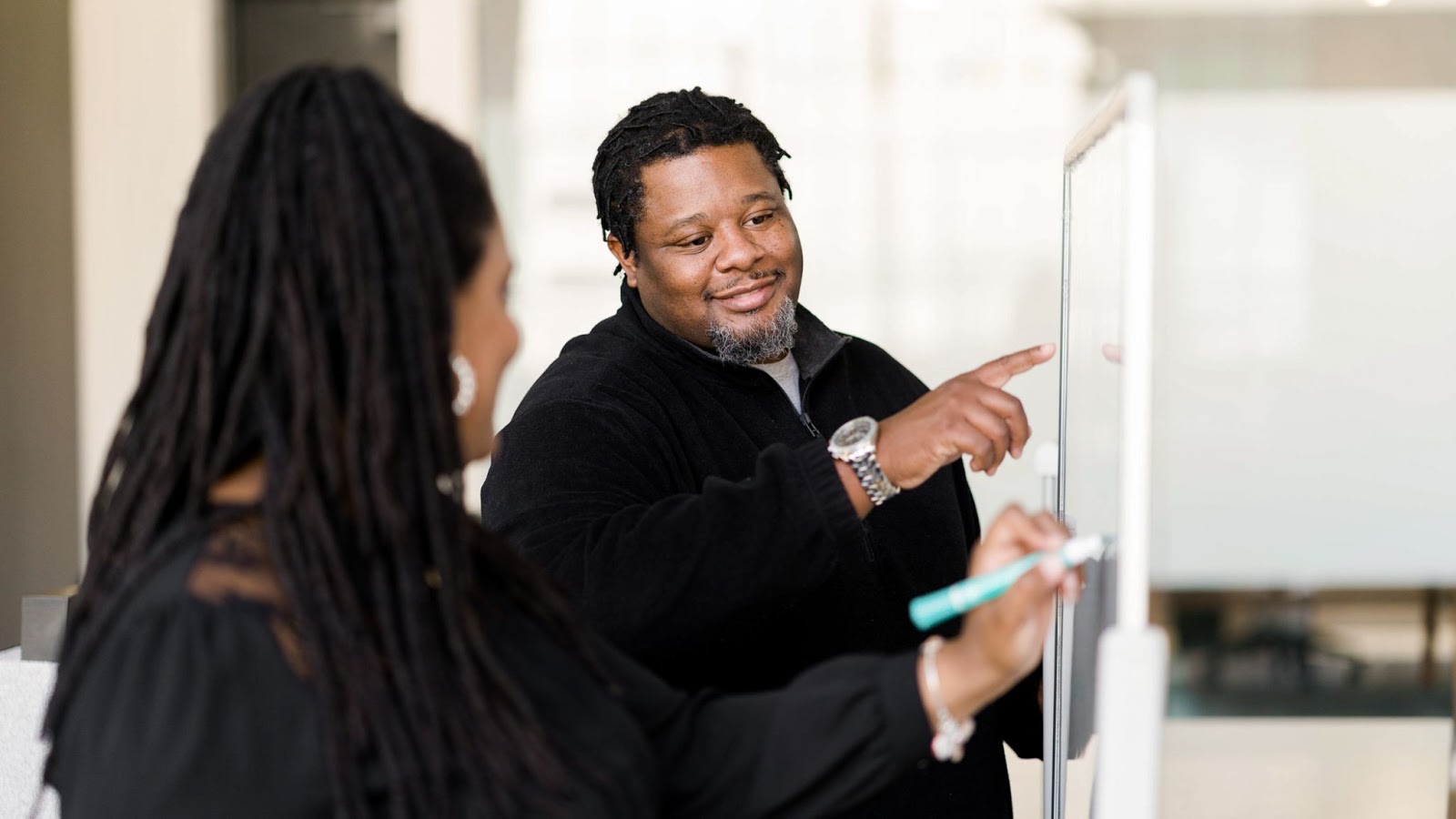 a man and a woman writing on a white board