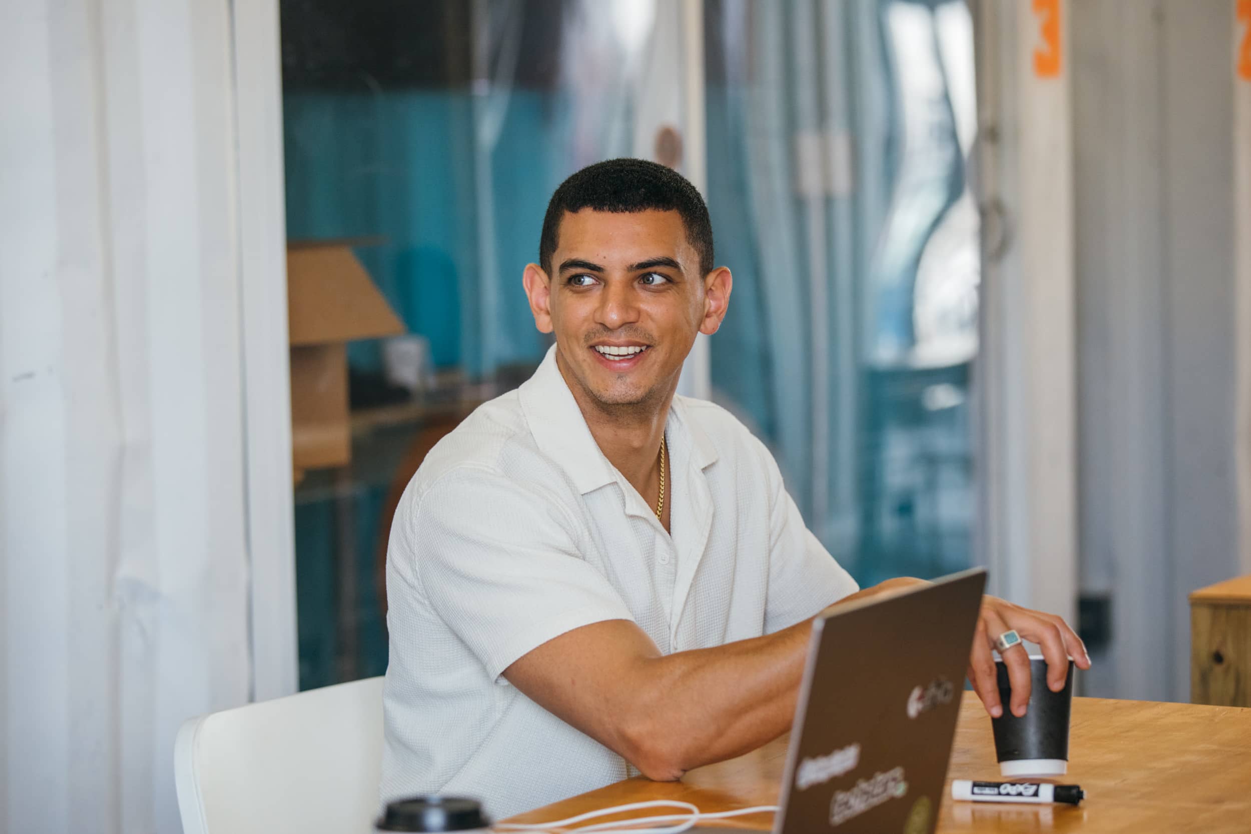 A man wearing white shirt is smiling at others in conference room.