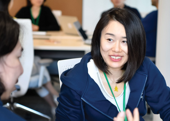 A woman in focus is smiling at other woman while sitting on chair