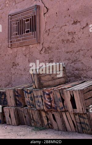 Empty wooden boxes for fruit and vegetables stacked against a typical, rustic Moroccan mud wall, Northern Africa. Stock Photo