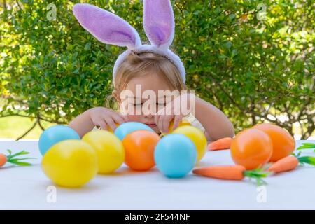 Cute Little Baby Dressed as Bunny Playing with Nice Colorful Eggs. Traditional Easter Decorations. Spring Christian Holiday Stock Photo