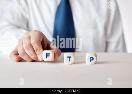 Hand of a businessman placing the wooden cubes with the word FTP file transfer protocol. Stock Photo