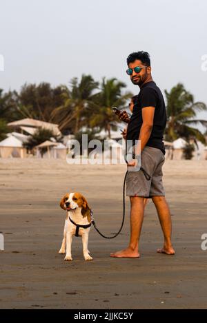 An Indian young man with dog at Ashwem Beach in Goa India Stock Photo