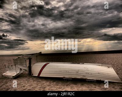 Dramatic New Jersey shore sunrise with sun's rays and lifeguard boat with snow fence, Stock Photo