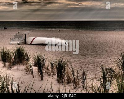 Dramatic New Jersey shore sunrise with sun's rays and lifeguard boat with snow fence, Stock Photo