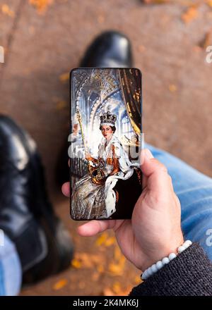 Belgrade, Serbia - October 03, 2022: Watching photos from coronation of Queen Elizabeth II on smartphone Stock Photo