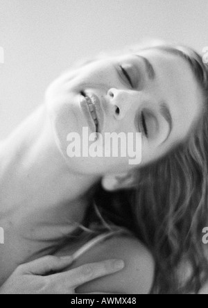 Woman with eyes closed tilting head and touching shoulder, portrait, close-up, black and white Stock Photo