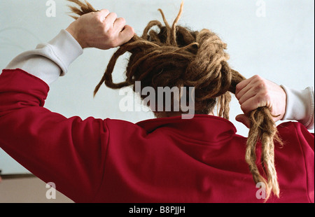 Man with long dreadlocks, tying them into bun, rear view Stock Photo