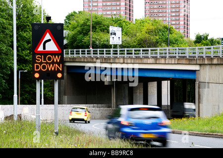 Electronic 'slow down' road sign indicating a bend in the road to the right.illuminated Stock Photo