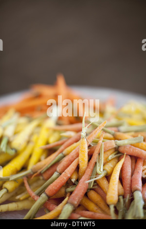 Organic vegetables in a dish Cooked orange yellow and pink heritage baby carrots Farm stand produce Stock Photo