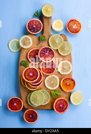 Assorted cut citrus fruits on cutting bord shot from above on light blue background Stock Photo