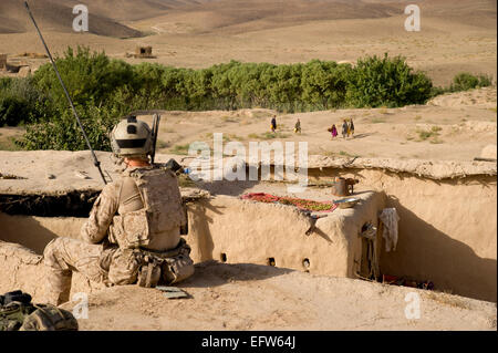 A US special forces soldier watches Afghan children carry water containers during a village clearing operation August 9, 2012 in Shah Wali Kot district, Kandahar province, Afghanistan. Stock Photo