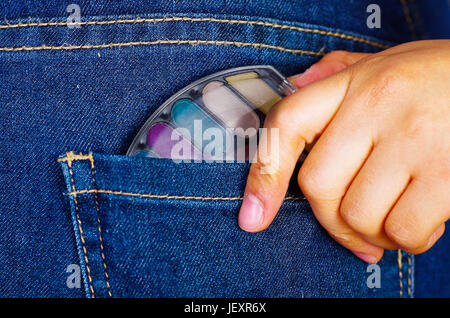 Woman hand holding a make up palette inside of jeans back pocket. Stock Photo