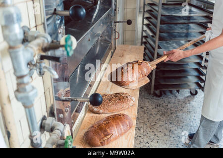 Woman in bakery putting bread on board Stock Photo