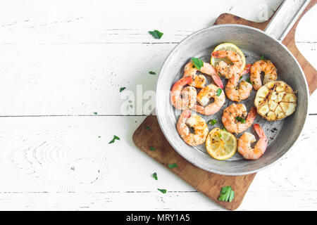 Roasted shrimps with lemon, garlic and herbs. Seafood, shelfish. Shrimps Prawns grilled with spices, garlic and lemon on white background, copy space. Stock Photo