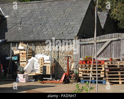 Empty wooden fruit and vegetable crates and pallets stacked outside the back of local farm shop Stock Photo