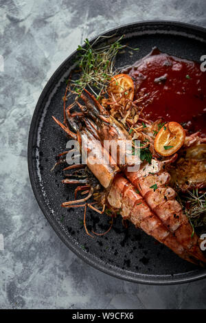 Grilled king prawns, with tomato sauce on a gray background, low key. Series concrete background. Food concept, food style, Copy space, food Stock Photo