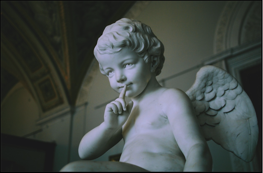 Photo of a sculpture, showing a child with wings with a finger over their lips